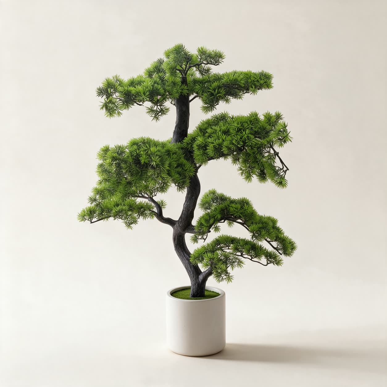 Artificial cloud-pruned pine bonsai about 95cm tall, tiered pads of fine green foliage on a twisting dark trunk, in a white ceramic planter on a warm off-white background