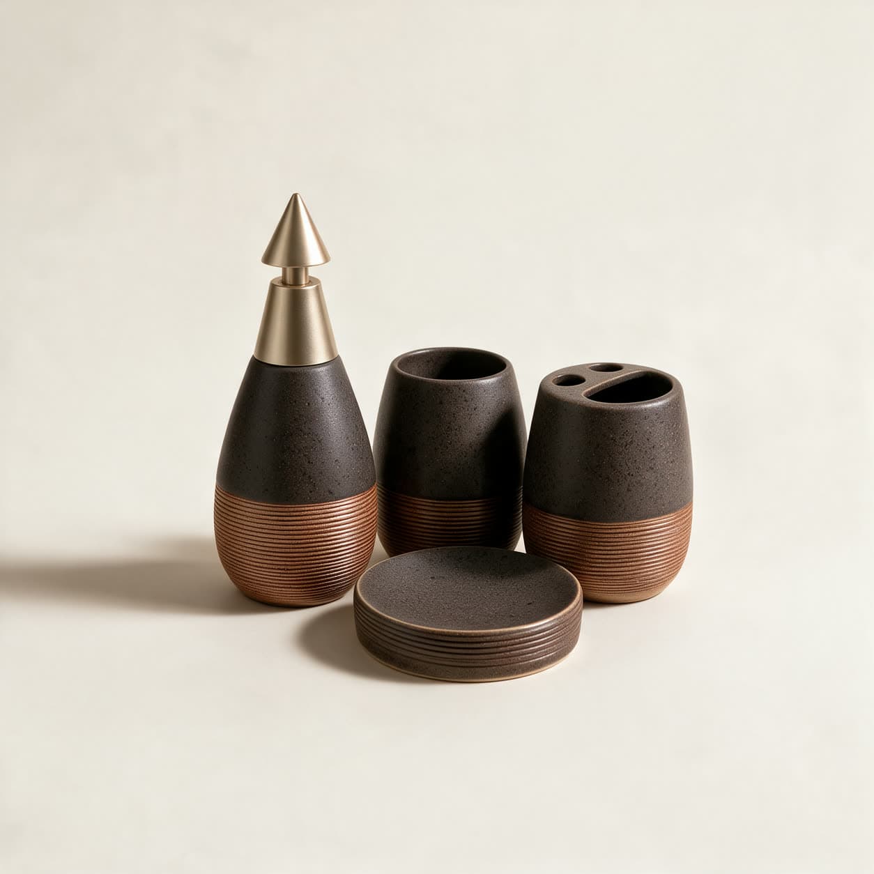 Four-piece dark charcoal speckled bathroom set with ribbed copper bands — teardrop soap dispenser, tumbler, toothbrush holder and round soap dish — on a warm off-white background