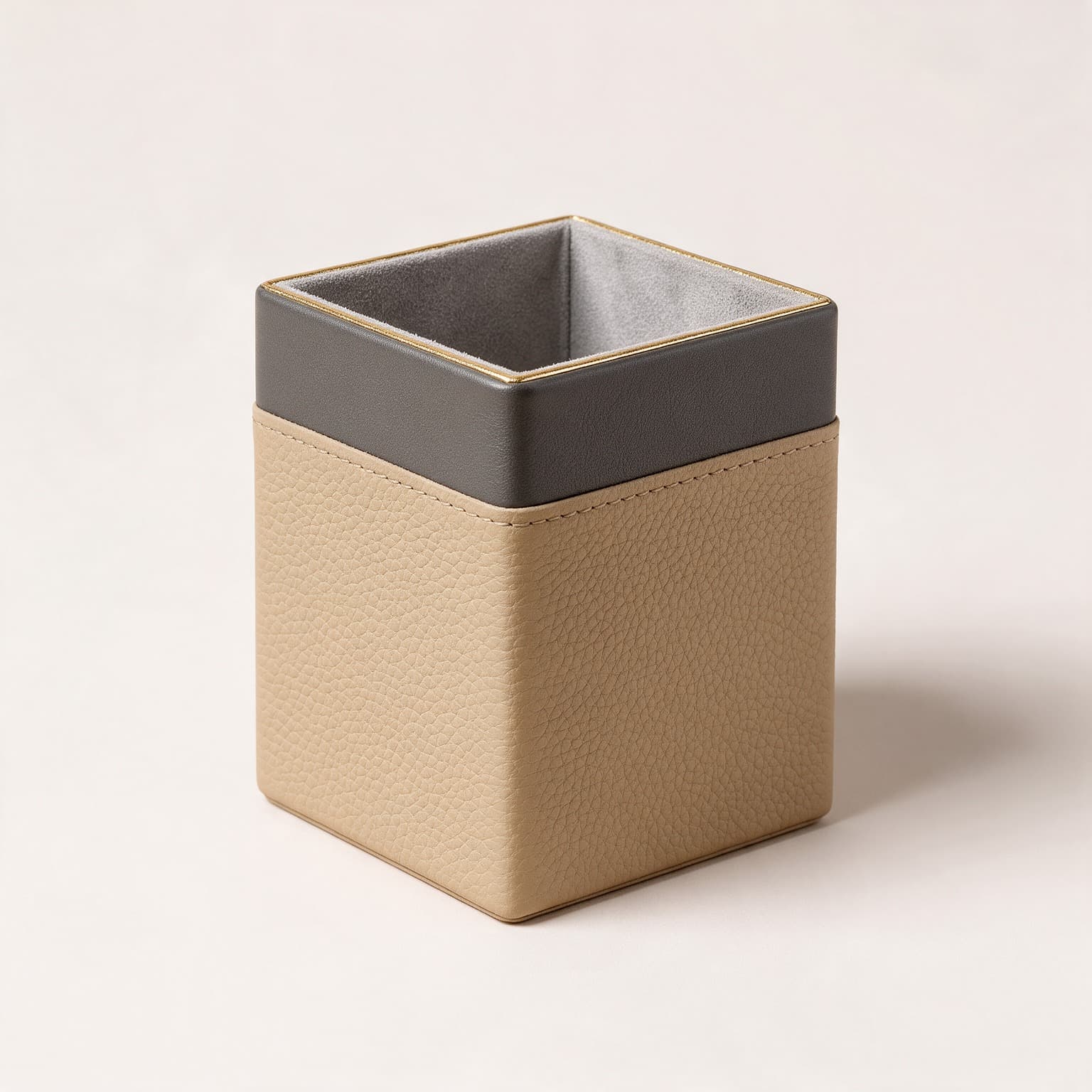 Square desk tidy in sand pebbled faux leather with a charcoal upper band, gold trim and a grey velvet lining