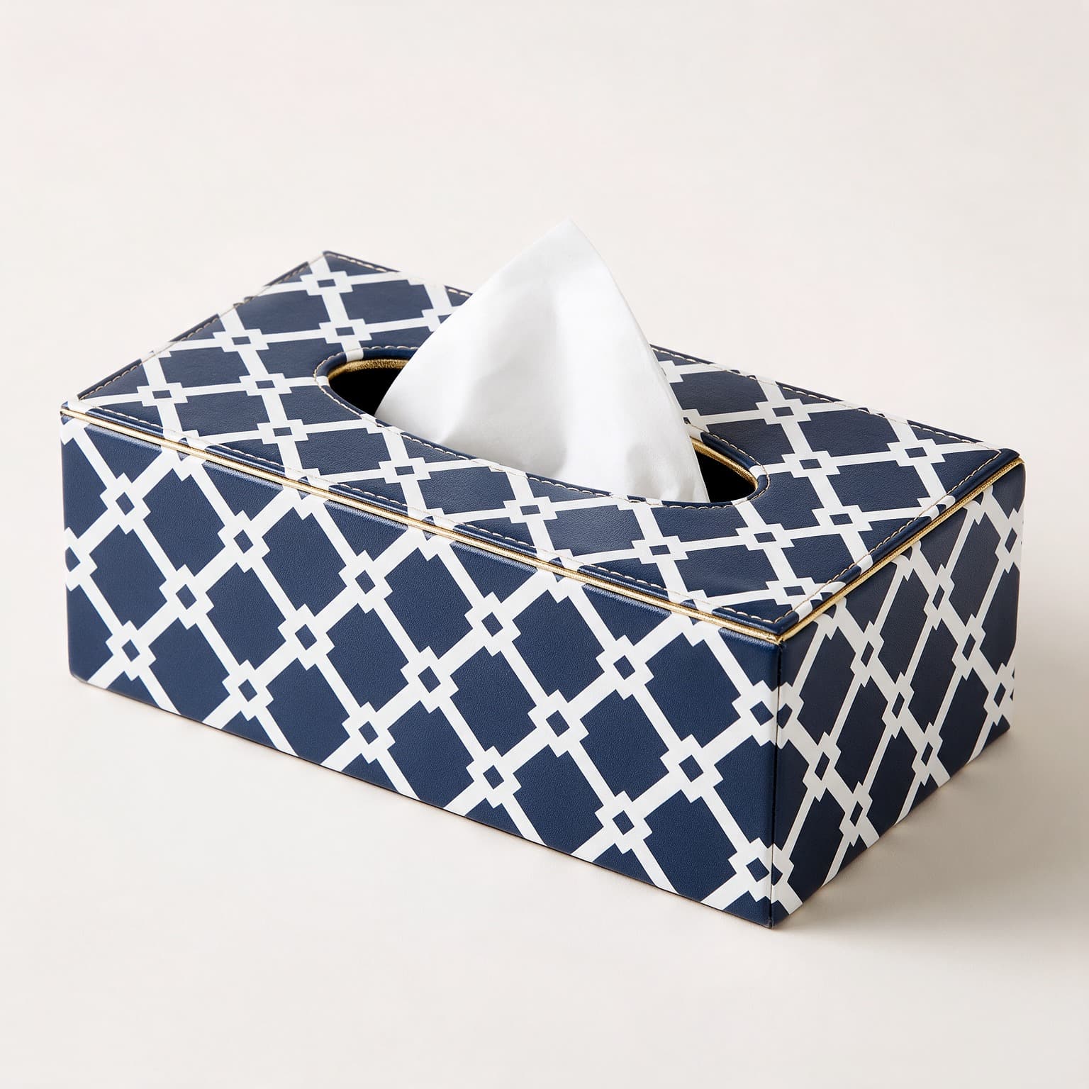 Rectangular tissue box cover in navy faux leather with a white geometric lattice print and gold trim