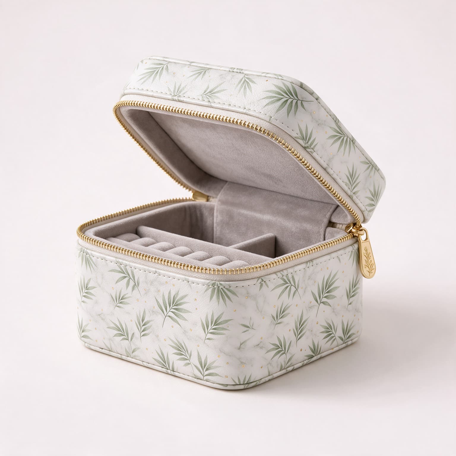 Open square jewellery box in marbled white faux leather printed with green leaves and gold flecks, lined in grey velvet with ring rolls